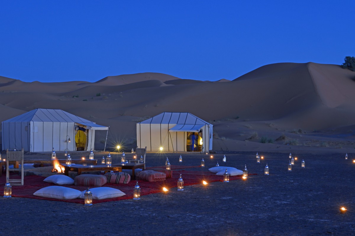 Marrocos: o país intenso e singular como você ainda não conhece - Acampamento chic, com luzes, tapetes e almofadas no deserto, com dunas atrás