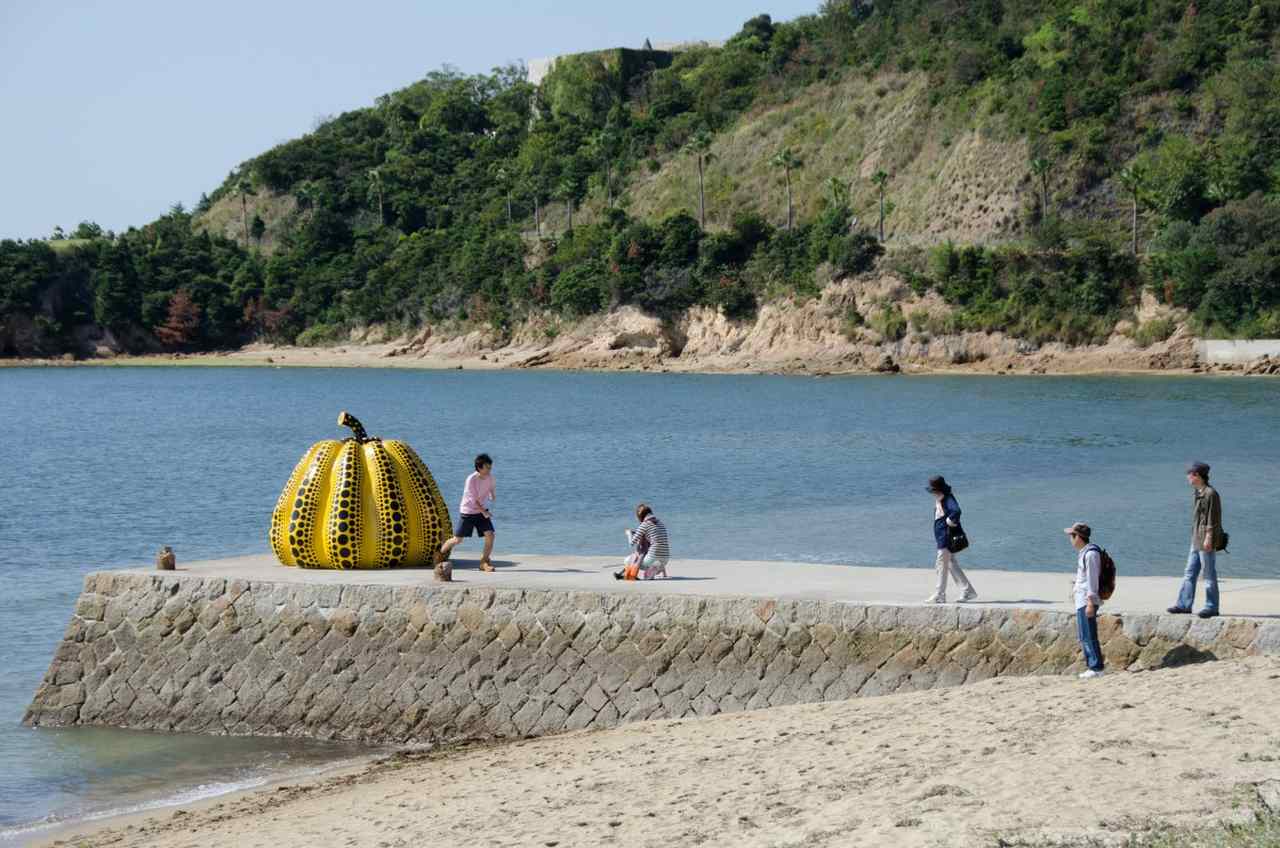 Conheça os melhores lugares para visitar no japão - escultura de abóbora gigante com pessoas fotografando e brincando ao redor, em ilha de Naoshima