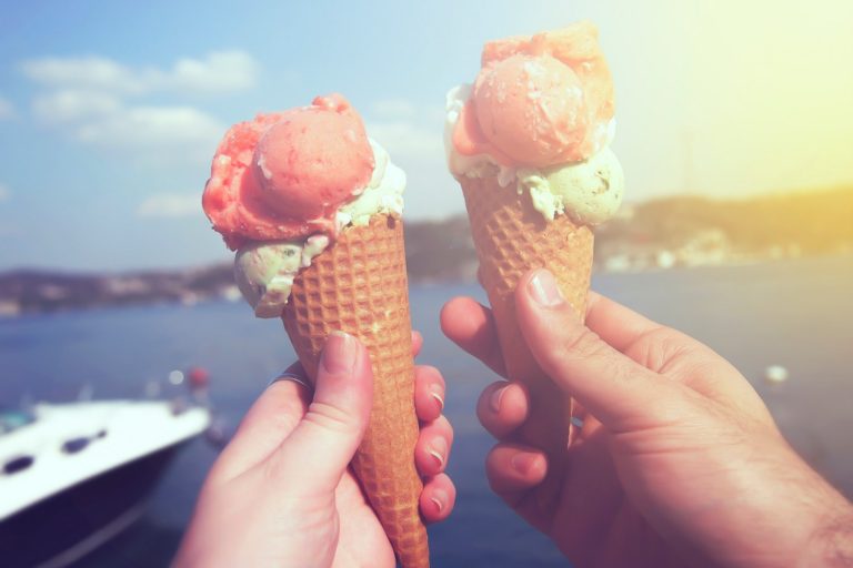 duas casquinhas de sorvete turco sendo seguradas por um casal com o mar ao fundo - Gastronomia e Doces Turcos — 14 Delícias que Você Não Pode Deixar de Provar! 