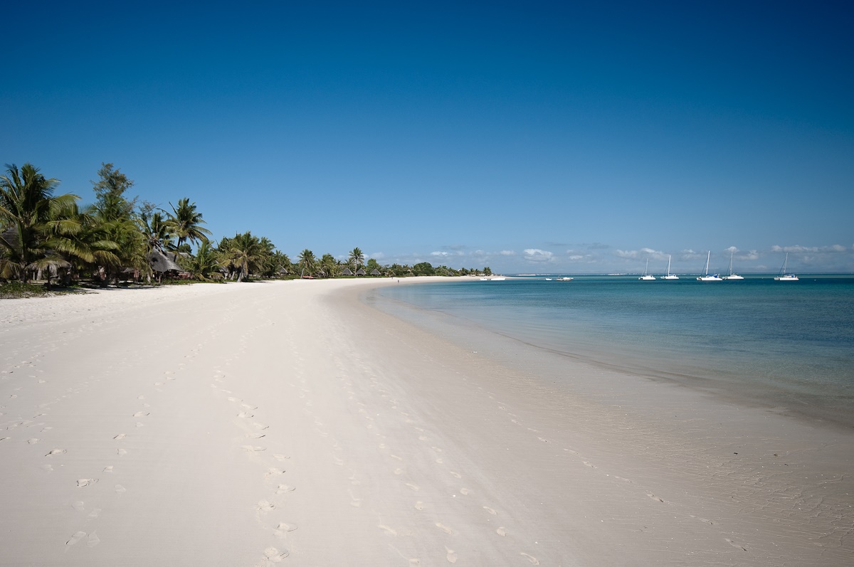 Praia de Moçambique, com areia clara e céu azul.